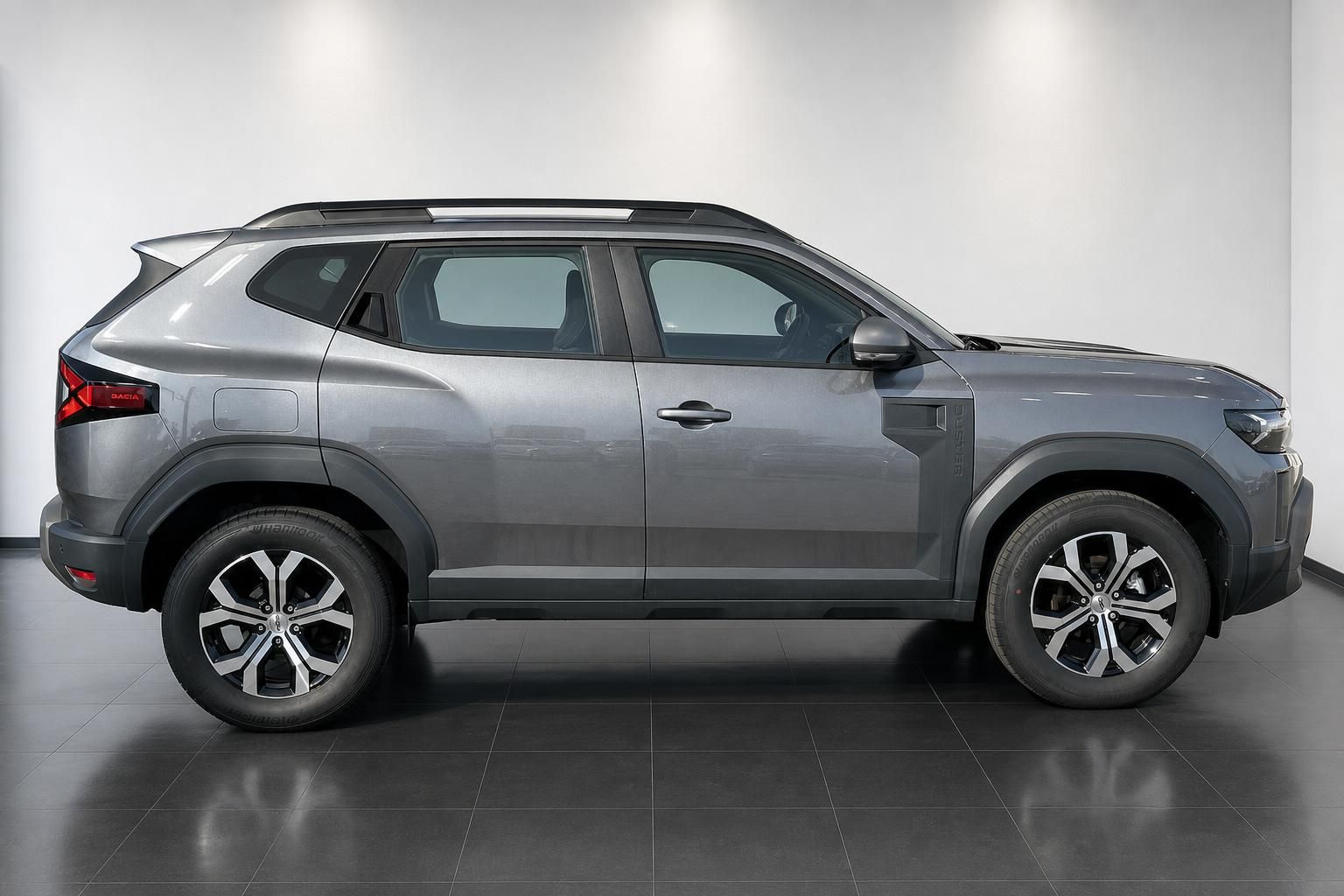 Dacia Duster SUV grau Seitenansicht mit Leichtmetallfelgen und schwarzem Dach im Autohaus