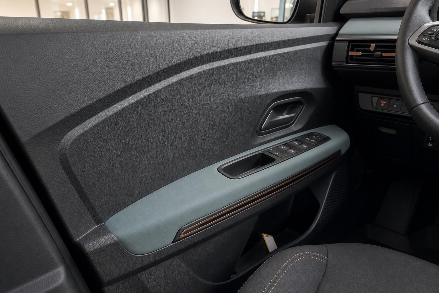 Fahrzeuginnenraum mit dunkler Verkleidung und Fensterheberbedienung in der Fahrertür