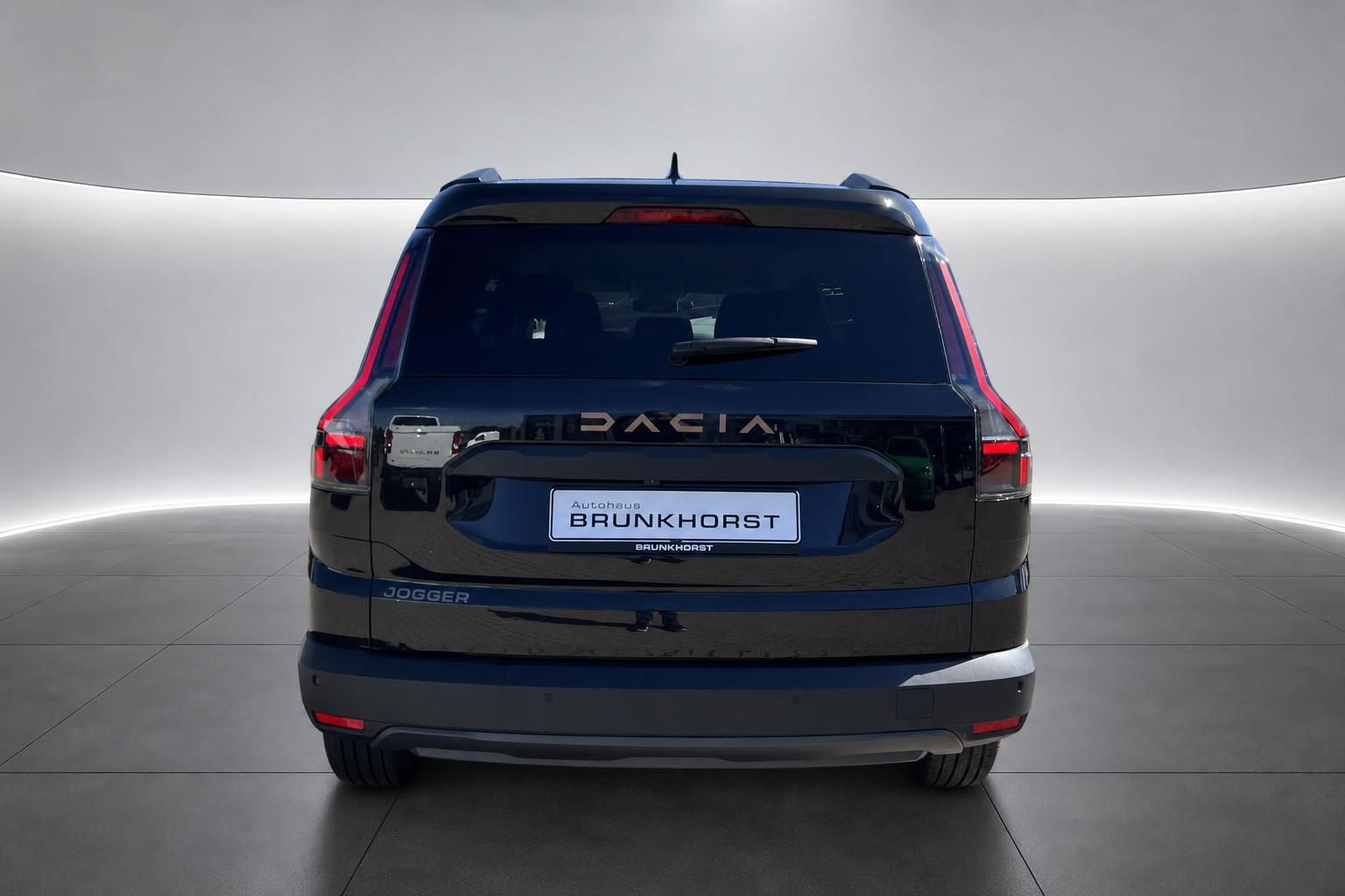 Dacia Jogger Heckansicht in Grau mit Autohaus Brunkhorst Kennzeichen im modernen Showroom