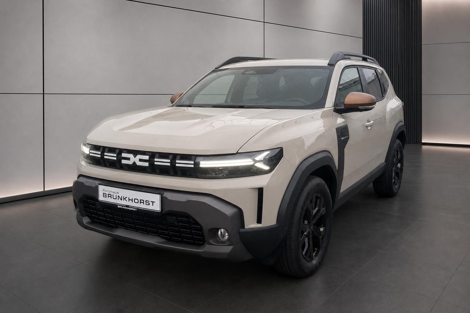 Dacia Duster Frontansicht in Beige mit Dachreling und schwarzen Felgen