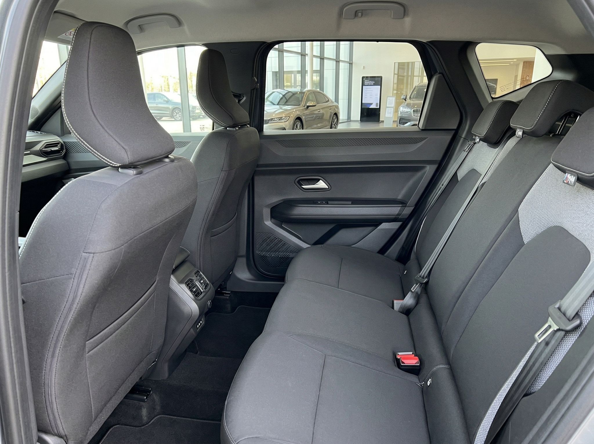 Dacia Rücksitzbank mit grauen Sitzen, Sicherheitsgurten und Blick durch Heckscheibe in Showroom