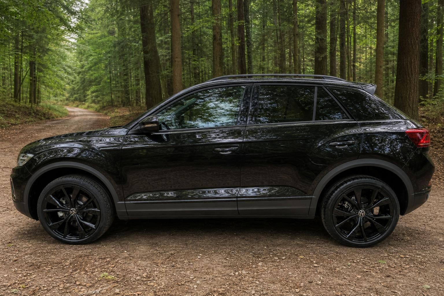 Schwarzer Volkswagen T-Roc SUV Seitenansicht in natürlicher Waldumgebung mit schwarzen Felgen