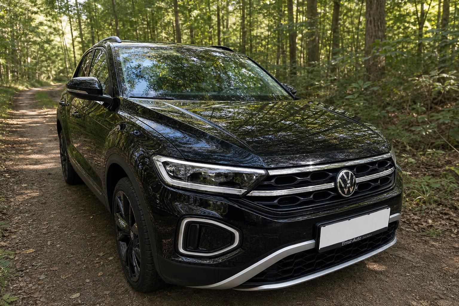 Volkswagen T-Roc Frontansicht in Schwarz mit LED-Scheinwerfern und VW-Kühlergrill im Wald