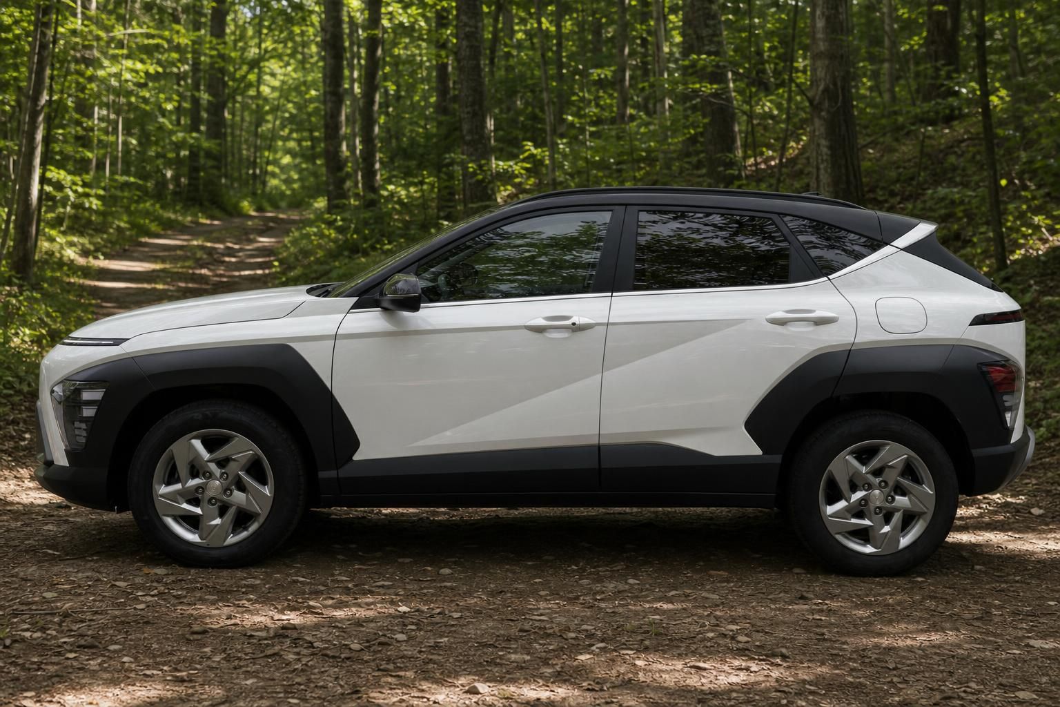 Hyundai Kona Electric weiß mit schwarzem Dach Seitenprofil auf Waldweg mit Alufelgen