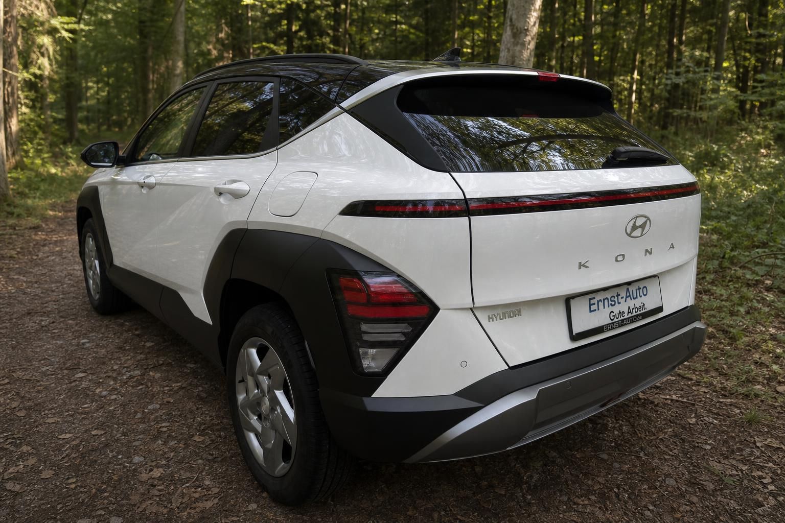 Weißer Hyundai Kona Elektro SUV von hinten im Wald
