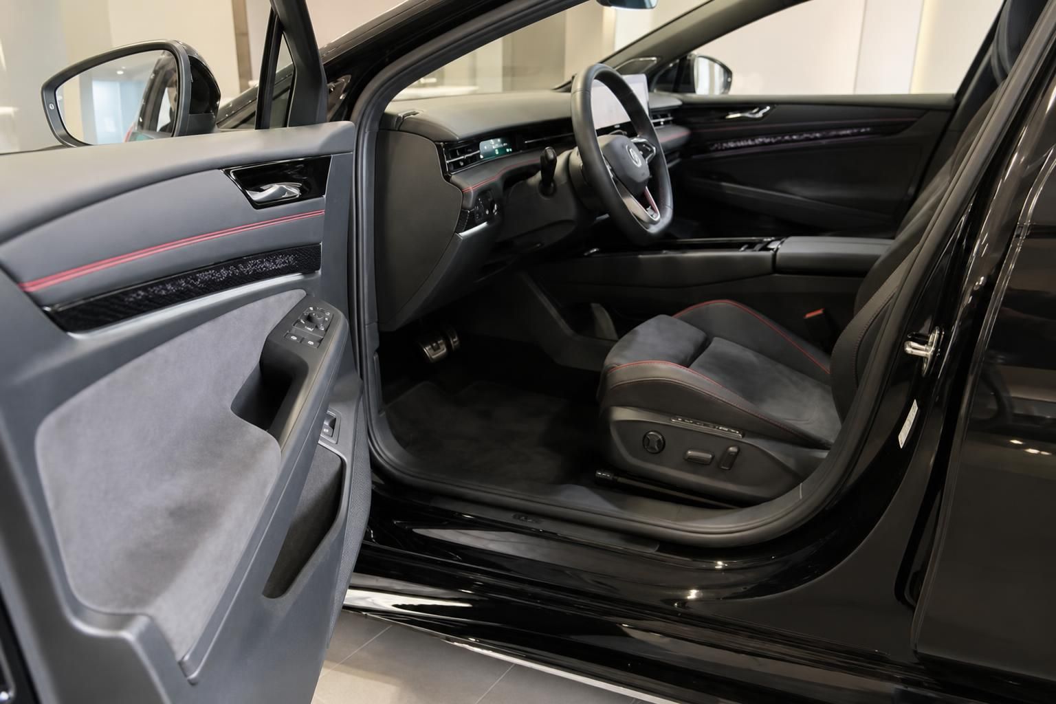 VW Innenraum schwarz mit roten Ziernähten, Blick auf Fahrersitz und Cockpit
