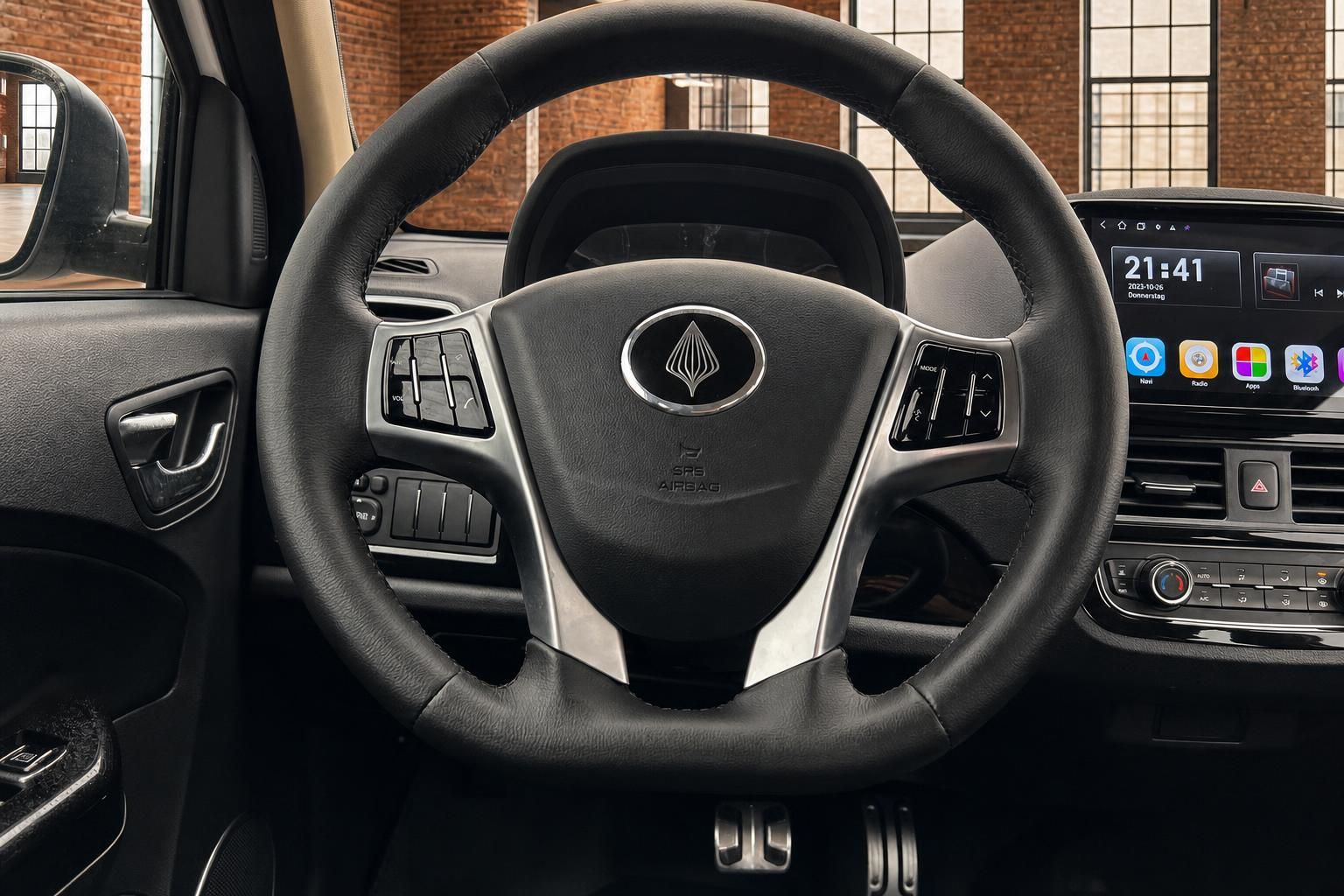 Fahrzeug Lenkrad Nahaufnahme mit Multifunktionstasten und Touchscreen-Infotainment im Hintergrund