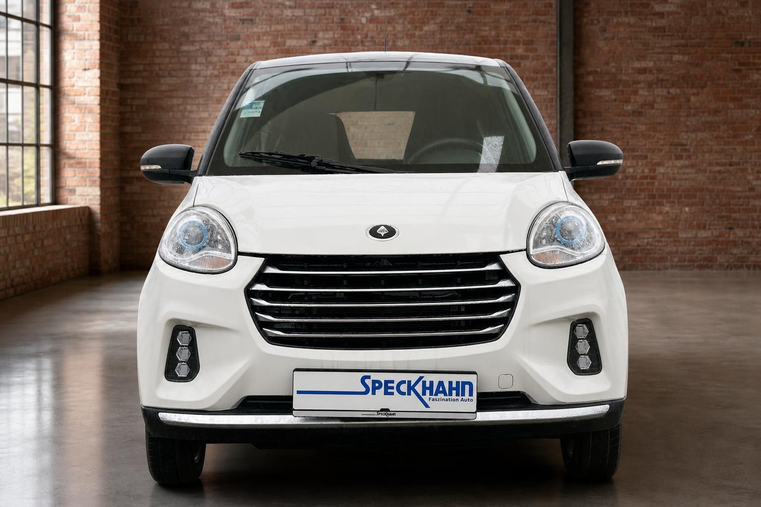 Weißes Elektroauto Frontansicht mit rundem Scheinwerfer und schwarzem Kühlergrill im Showroom