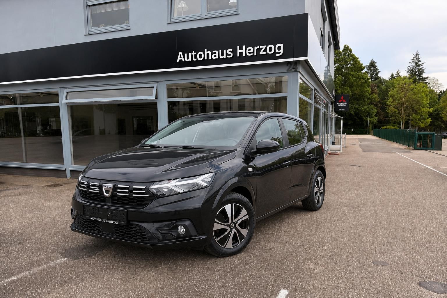 Dacia SUV in Dunkelgrau vor Autohaus Herzog - Außenansicht Frontperspektive