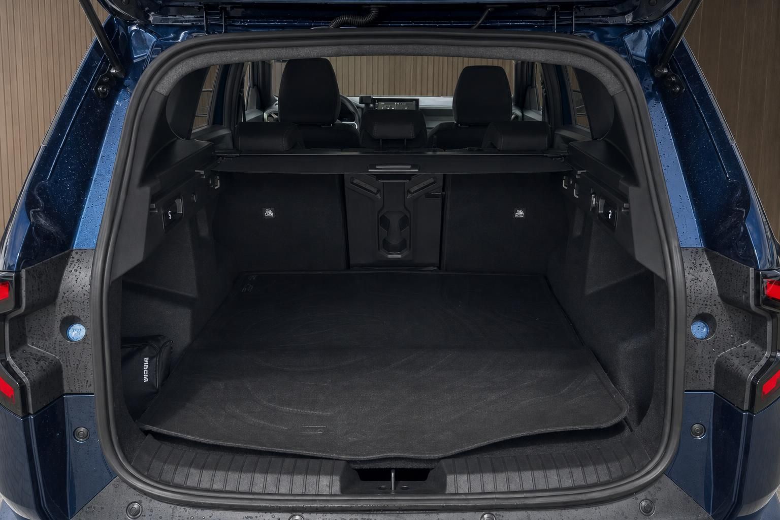 Kofferraum-Innenansicht eines blauen SUVs mit geöffneter Heckklappe und schwarzer Ladeflächenauskleidung