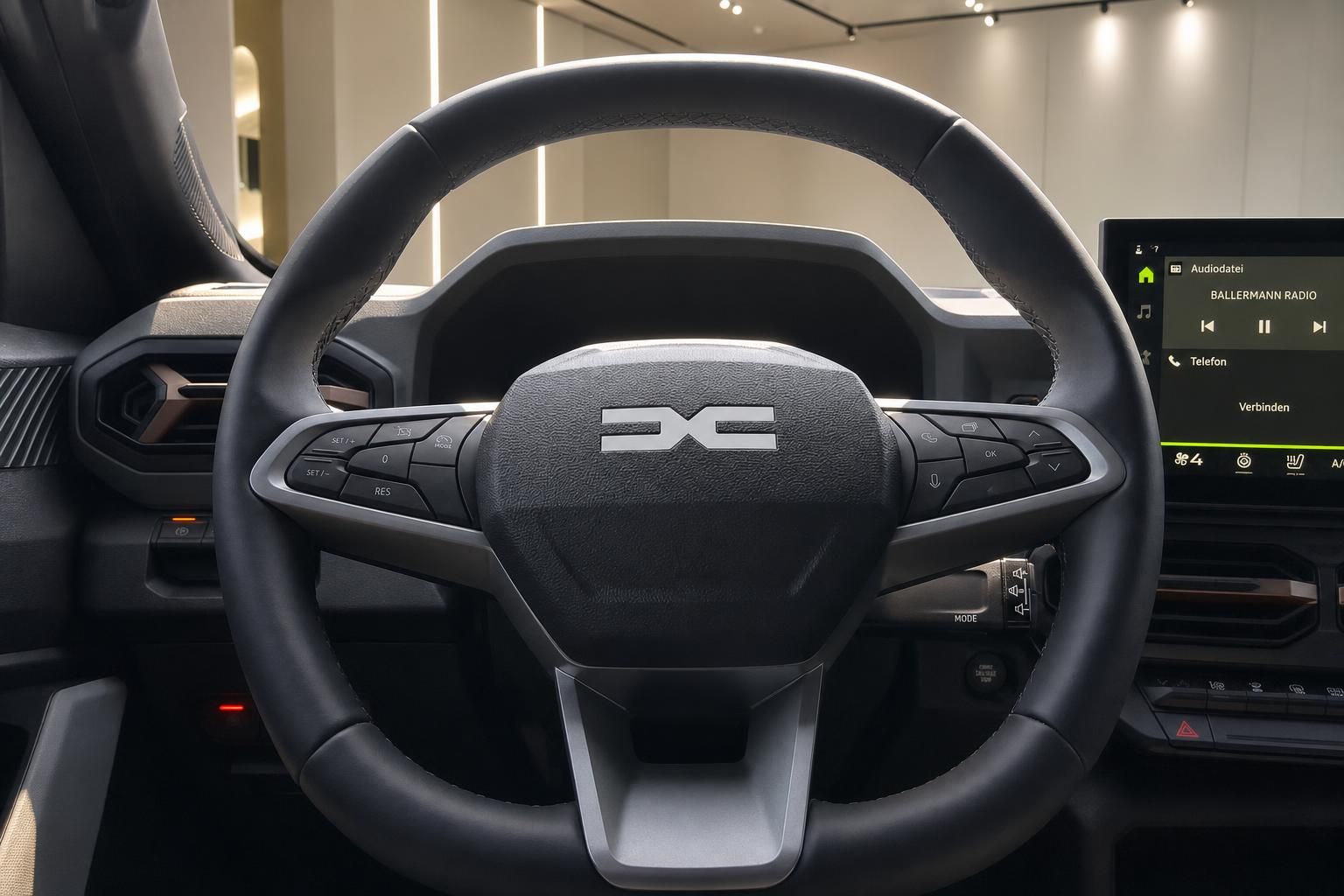Dacia Lenkrad mit Multifunktionstasten und Infotainment-Display im Fahrzeuginnenraum