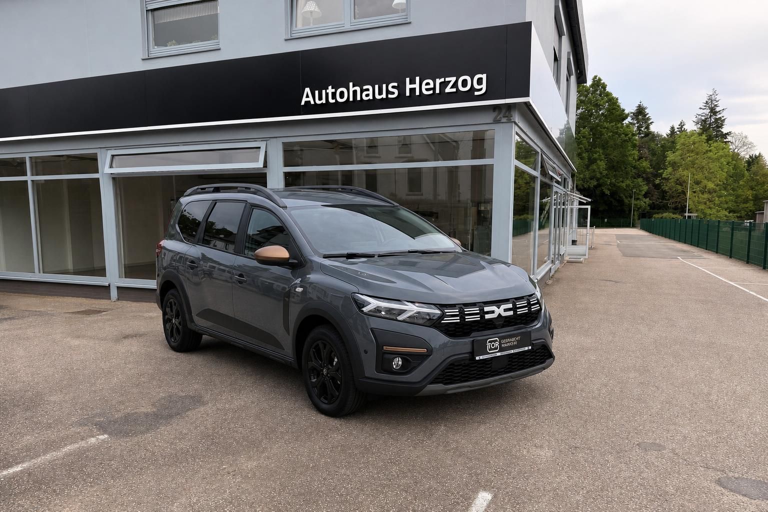 Dacia Jogger grau als SUV vor Autohaus Herzog, Frontansicht
