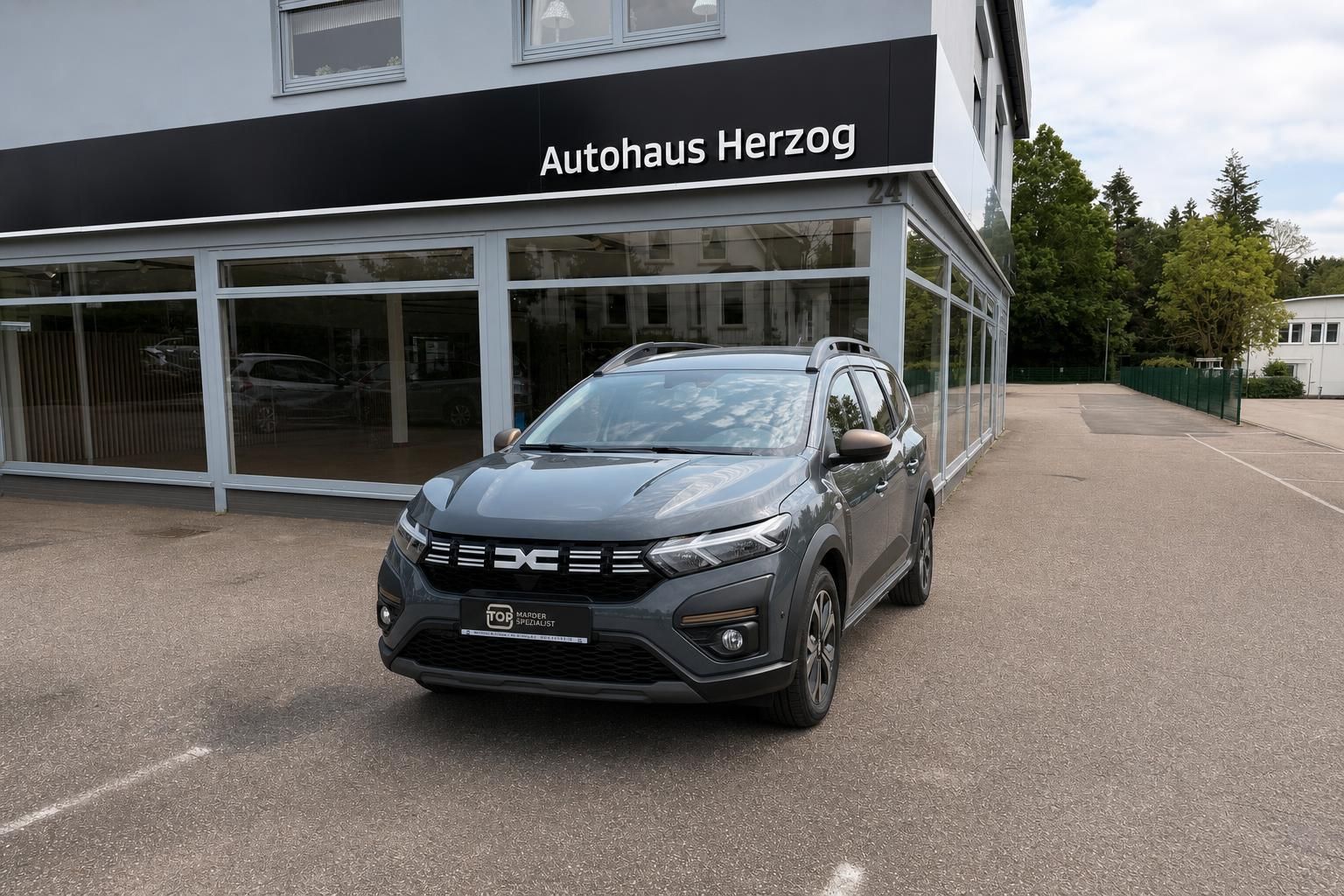 Dacia Jogger in Grau, Frontansicht vor Autohaus Herzog geparkt