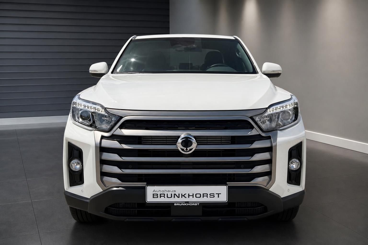 Frontansicht weißer Pickup-Truck mit markanter Kühlergrill und LED-Scheinwerfern im Showroom