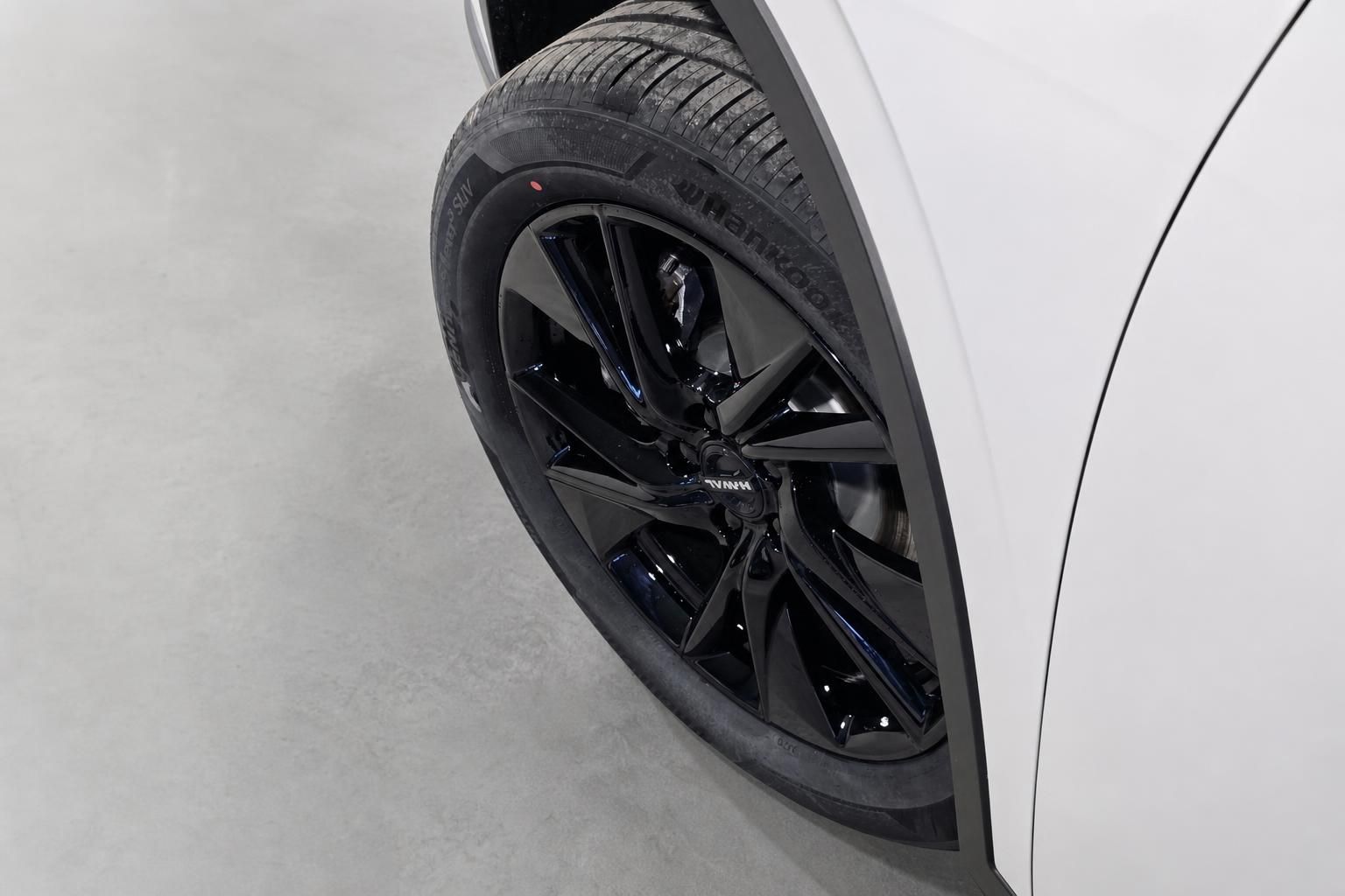 Nahaufnahme schwarzer Alufelge mit Hankook-Reifen am weißen SUV