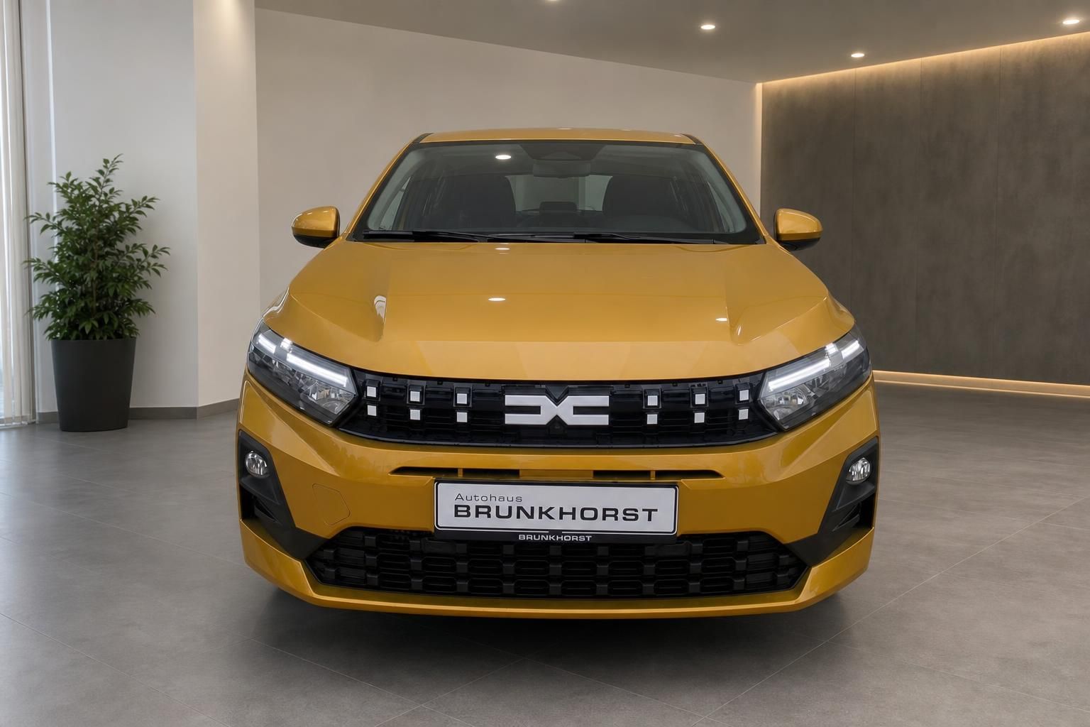 Dacia Sandero gelb Frontansicht mit LED-Scheinwerfern im Showroom
