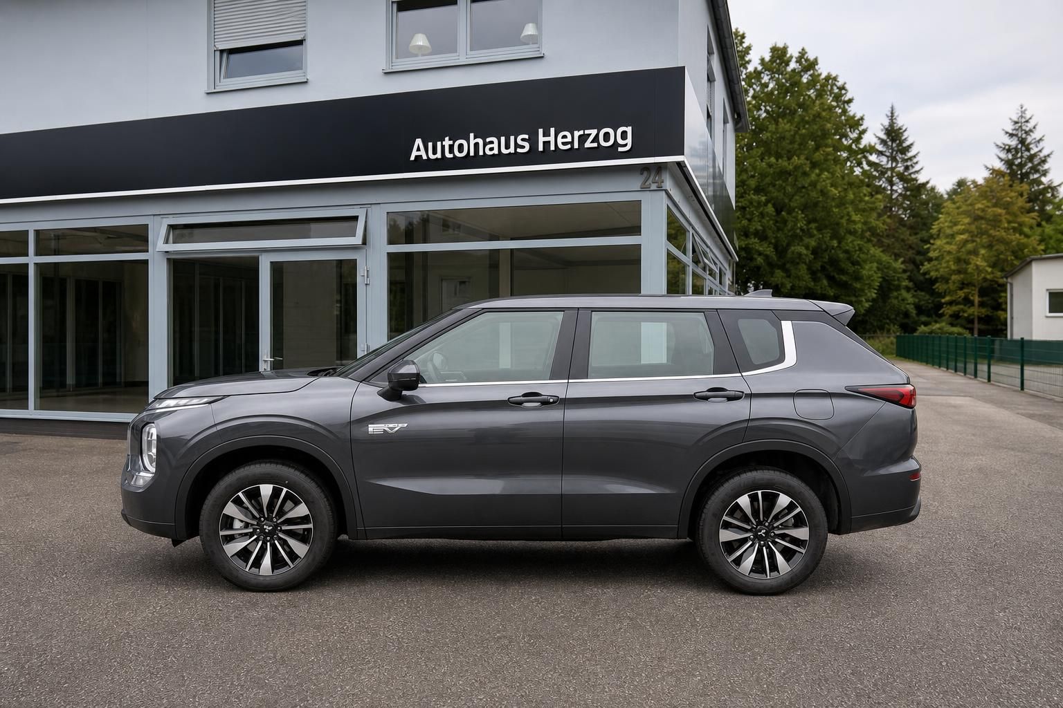 Mitsubishi Outlander PHEV Grau, Seitenansicht vor Autohaus Herzog