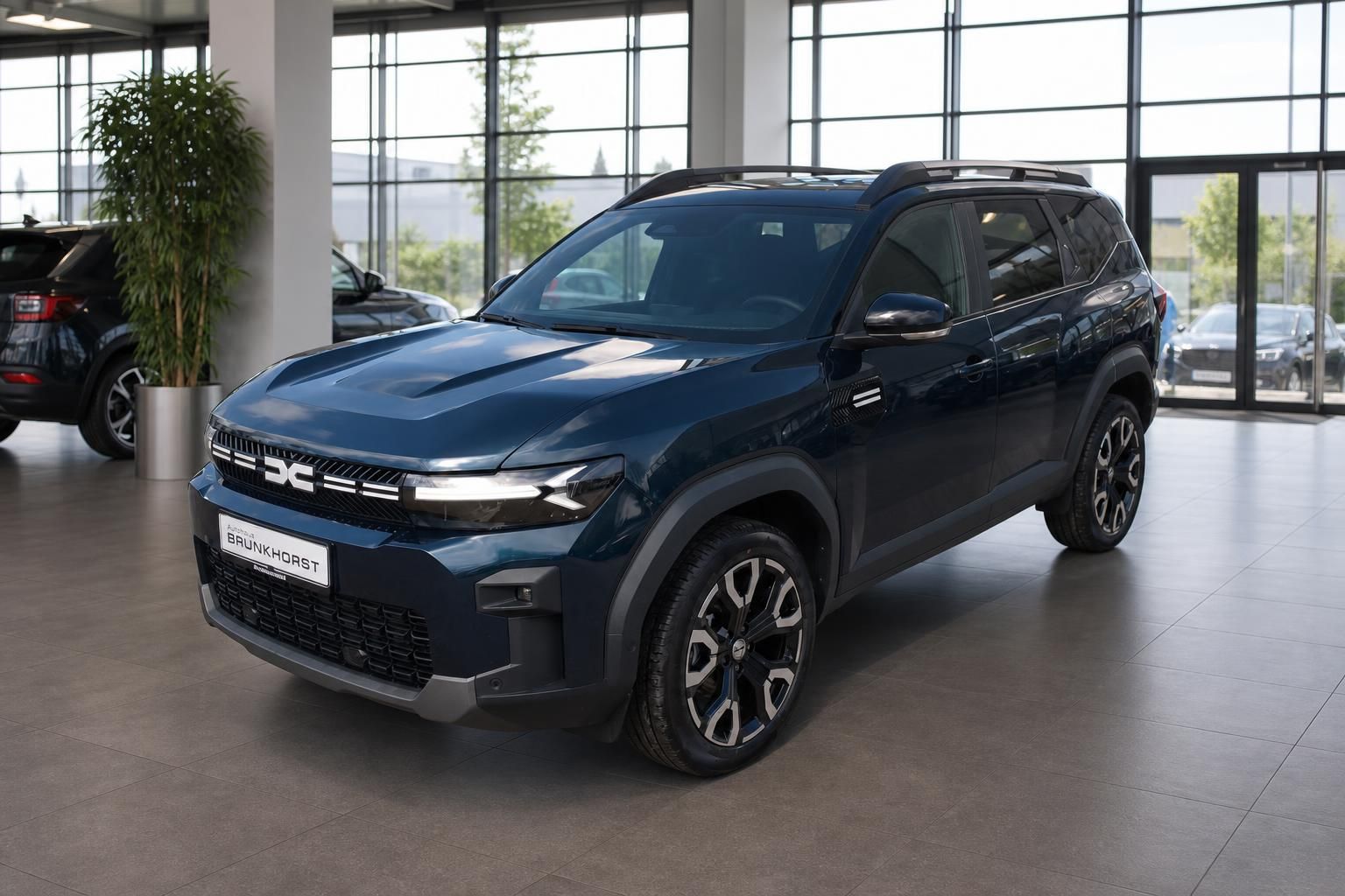 Dacia SUV Seitenansicht in dunkelblau mit Dachreling im modernen Autohaus Showroom