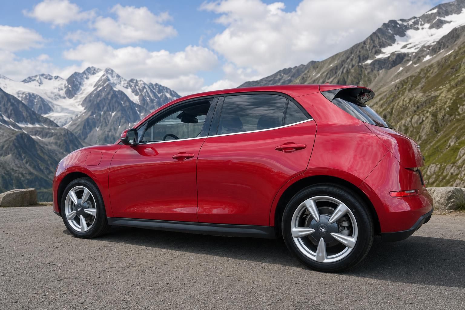 Roter Kleinwagen Seitenansicht von rechts hinten vor alpiner Berglandschaft mit Schnee