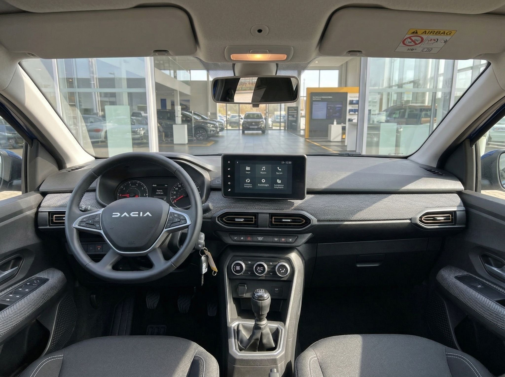 Dacia Innenraum mit Lenkrad, Touchscreen und modernem Armaturenbrett in grau