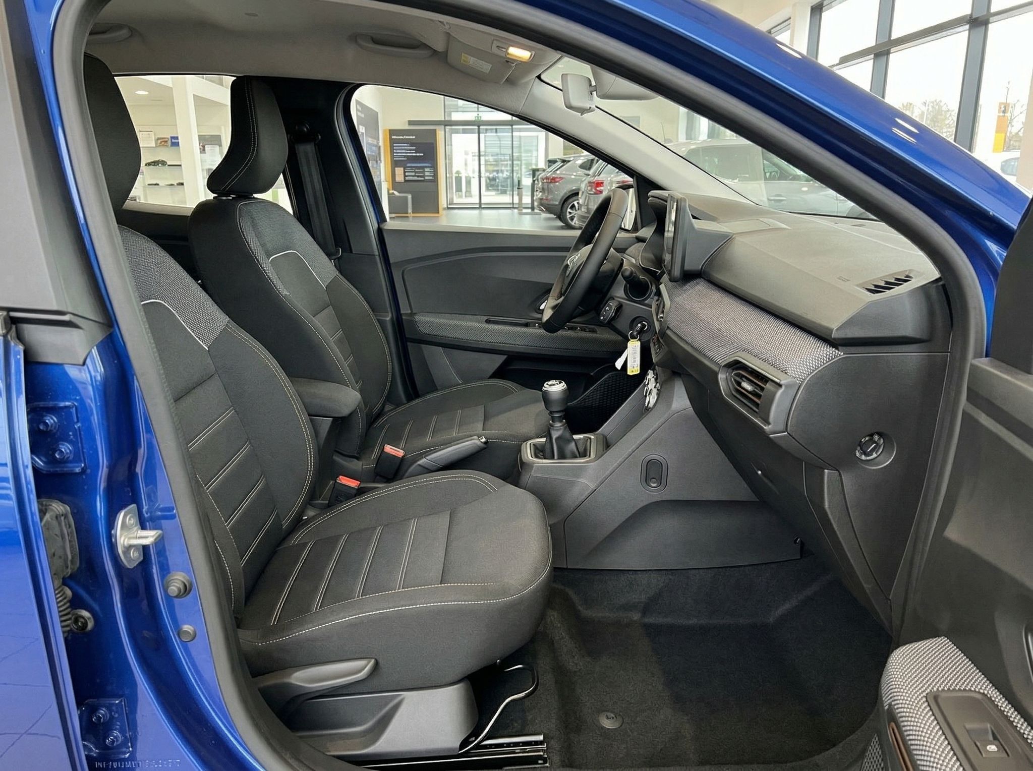 Dacia Innenraum Beifahrerseite mit schwarzen Stoffsitzen und Schaltknauf
