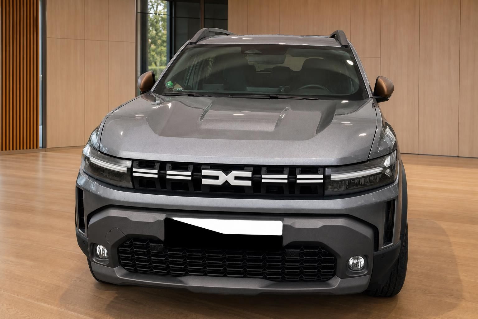 Dacia Duster grau Frontansicht gerade mit Dacia-Logo und Kühlergrill im Showroom