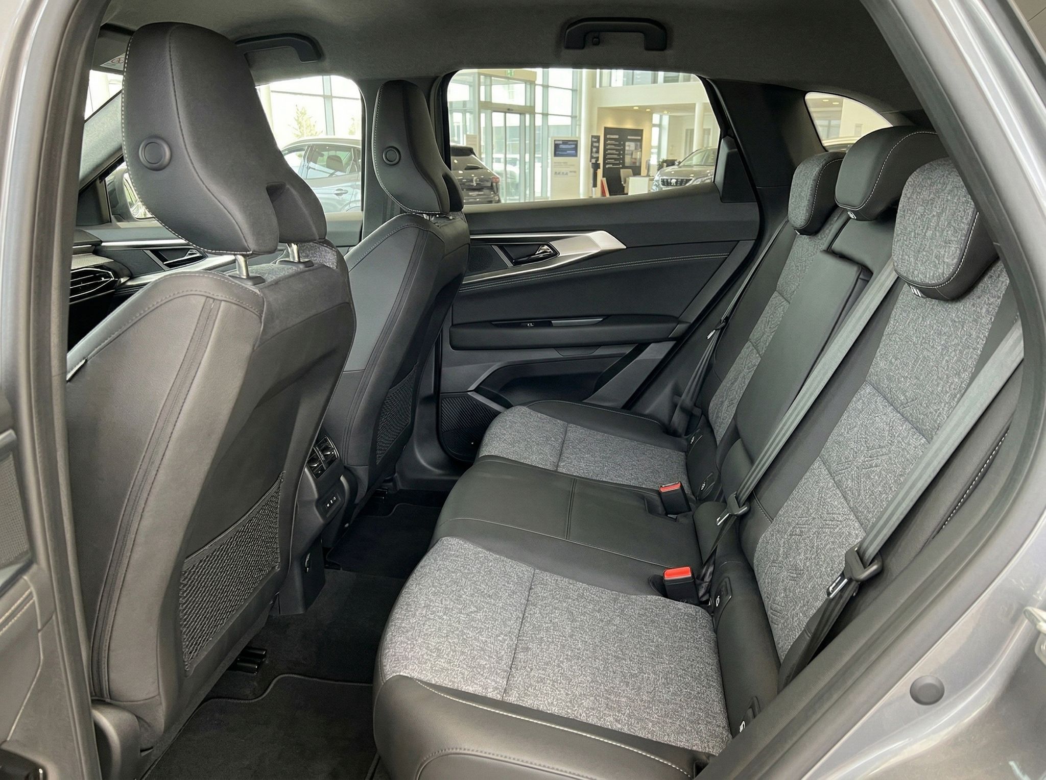 Rücksitzbank mit grauen Stoffsitzen und Blick durch Panoramafenster ins Autohaus
