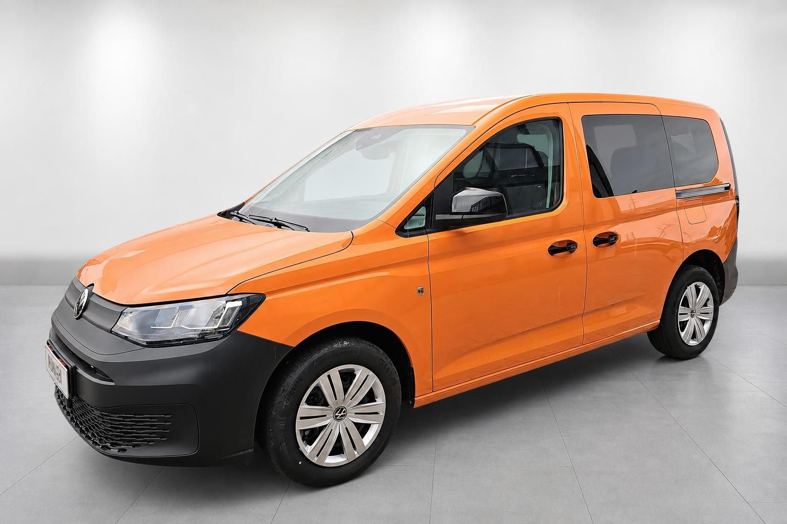 VW Caddy in Orange, Seitenansicht schraeg von vorne