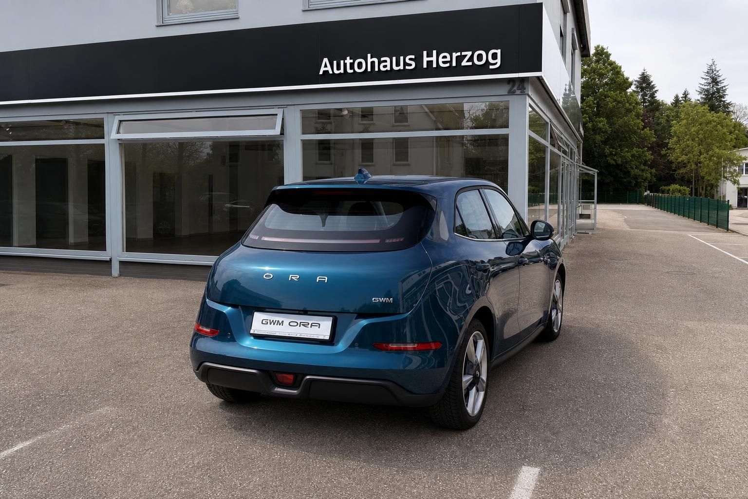 GWM Ora blau metallic, Heckansicht seitlich vor Autohaus Herzog