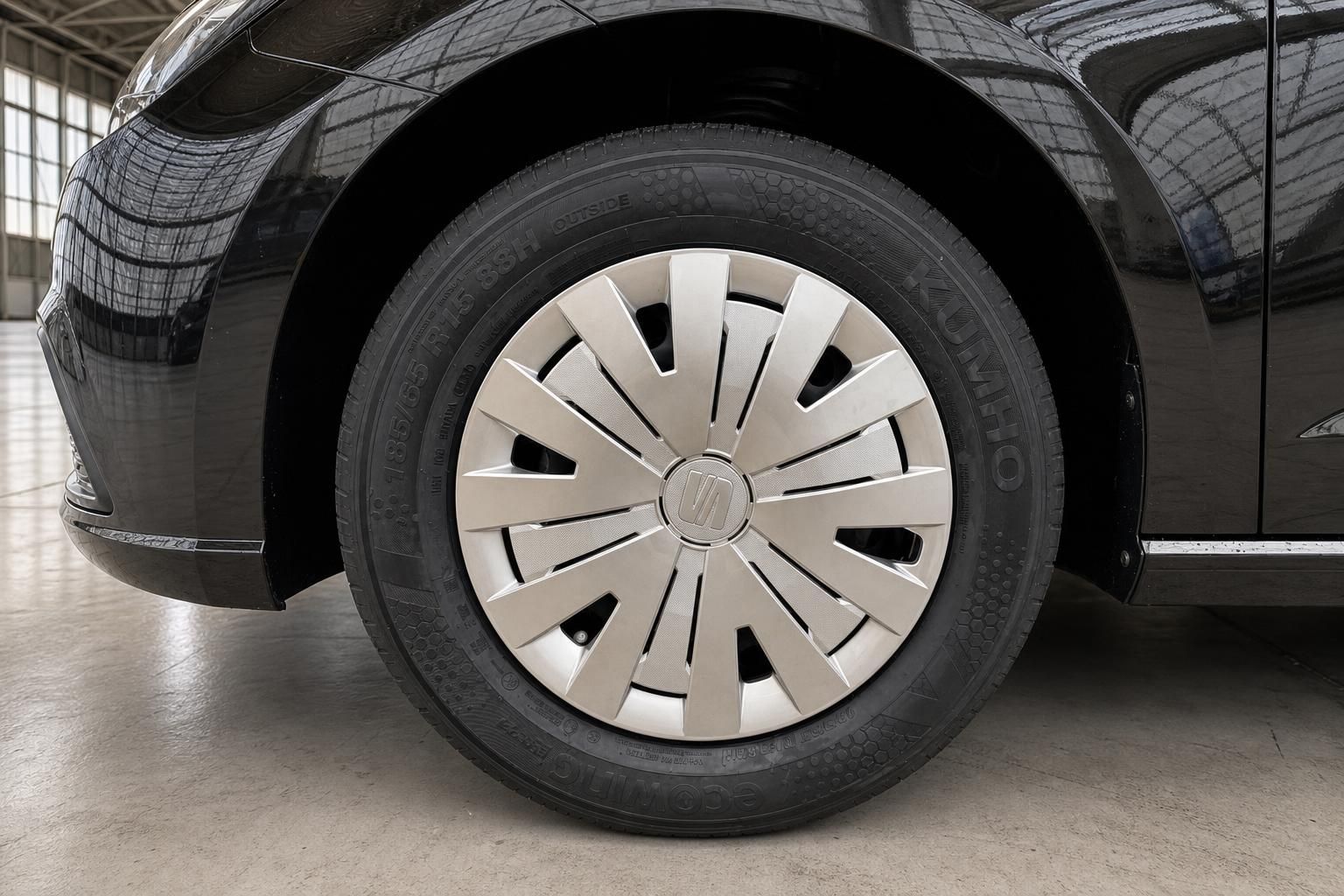 Detailaufnahme Fahrzeugrad mit silbernen Radkappen und schwarzer Karosserie