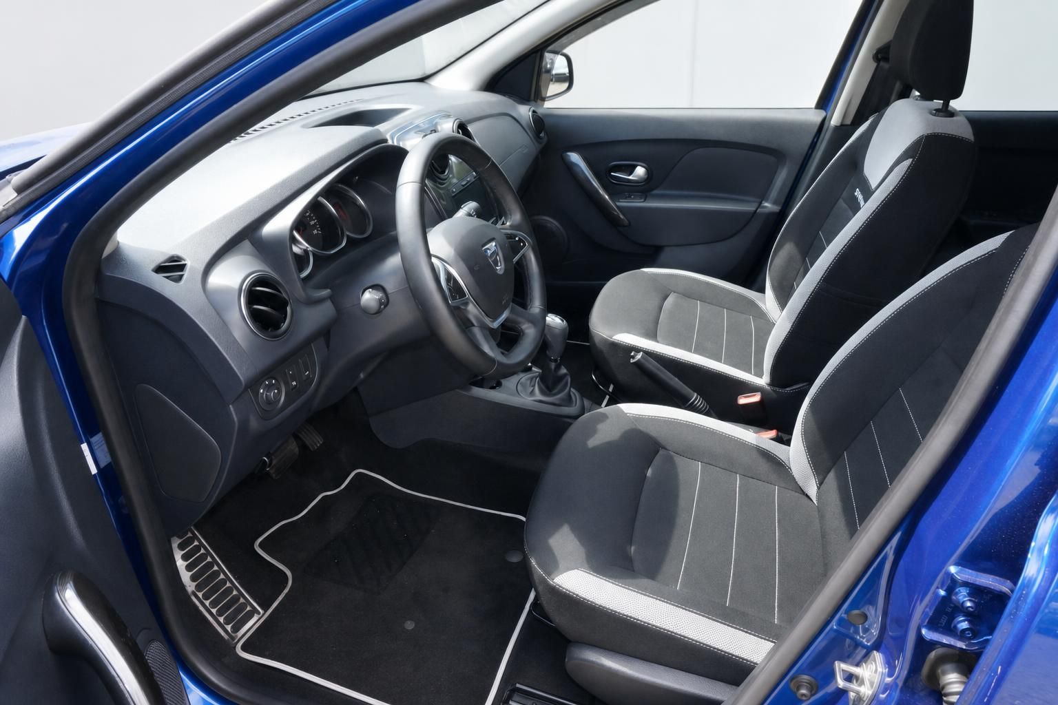 Dacia Innenraum Fahrerseite mit Sitzen, Lenkrad und blauer Karosserie