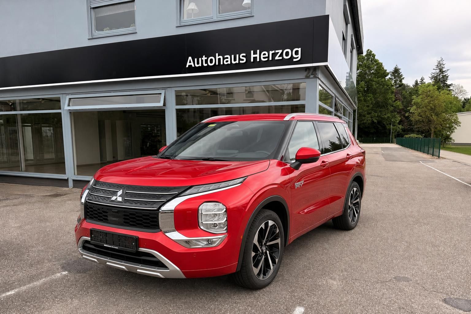 Roter Mitsubishi Outlander SUV vor Autohaus Herzog