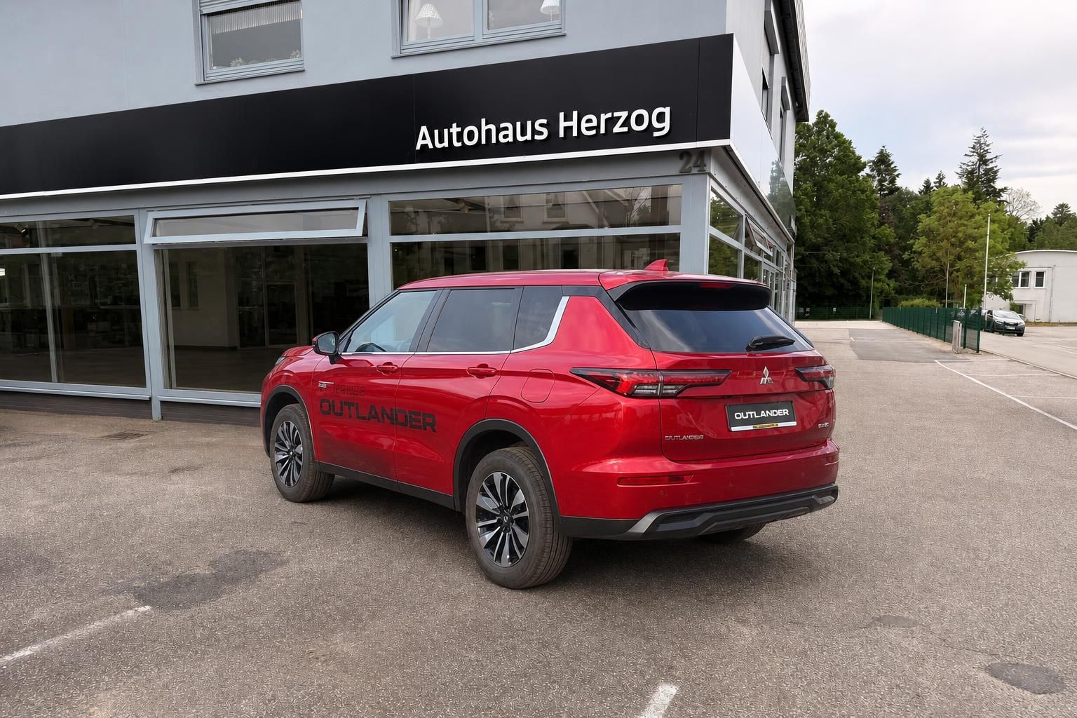 Mitsubishi Outlander in Rot, Heckansicht vor Autohaus Herzog