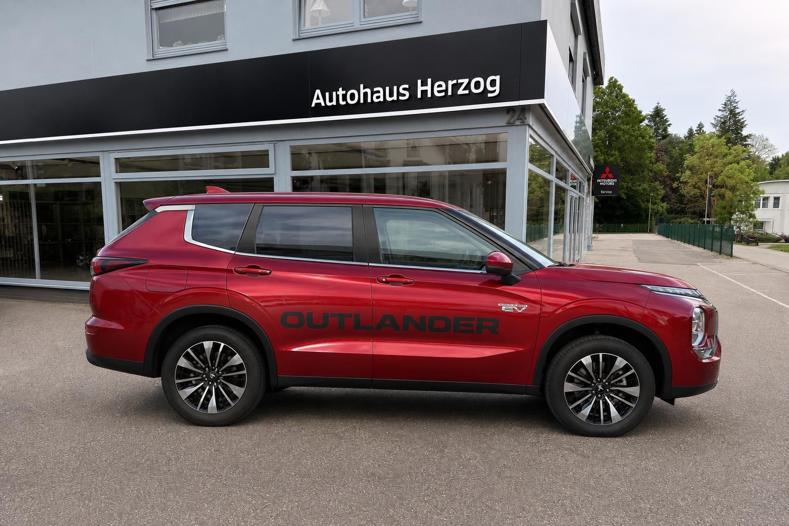 Mitsubishi Outlander PHEV in Rot, Seitenansicht vor Autohaus Herzog