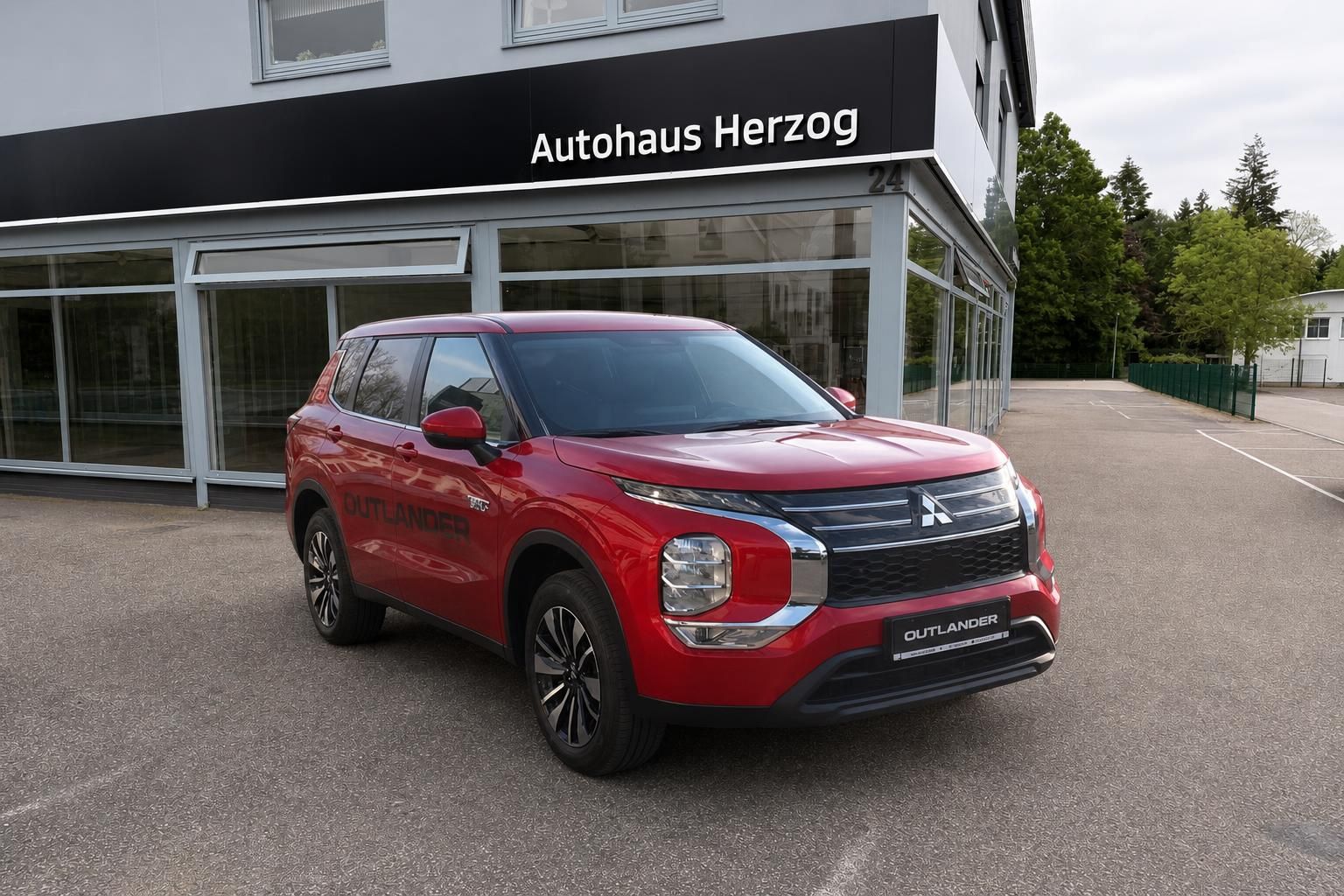 Mitsubishi Outlander in Rot, Frontansicht schraeg vor Autohaus Herzog