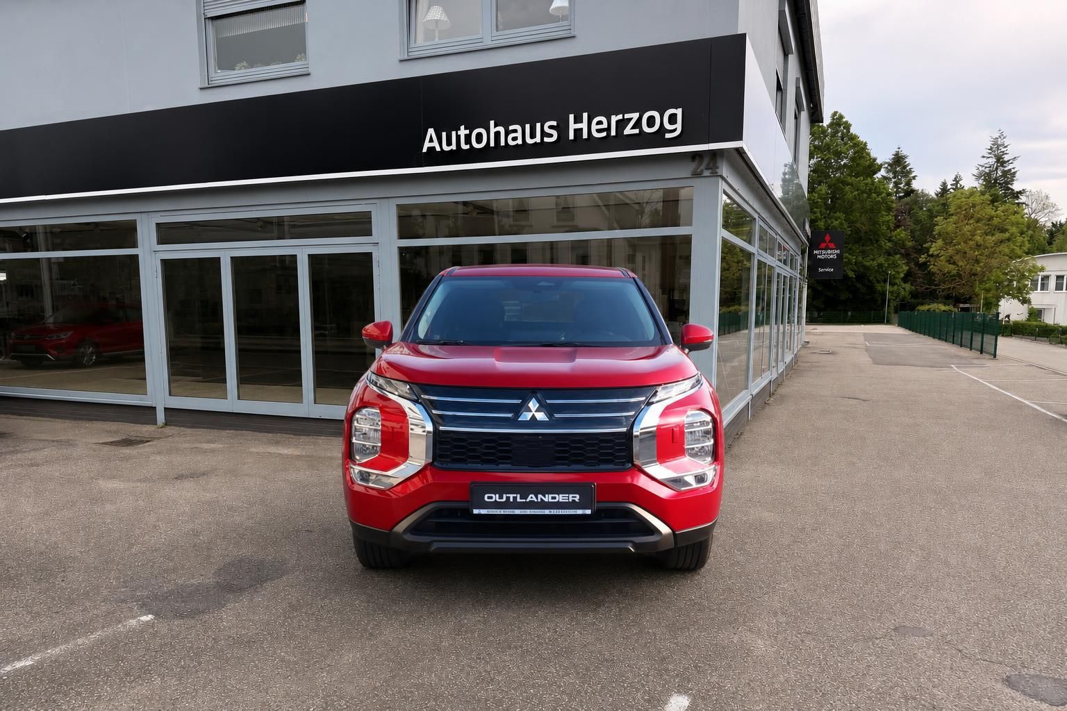 Mitsubishi Outlander in Rot, Frontansicht vor Autohaus Herzog