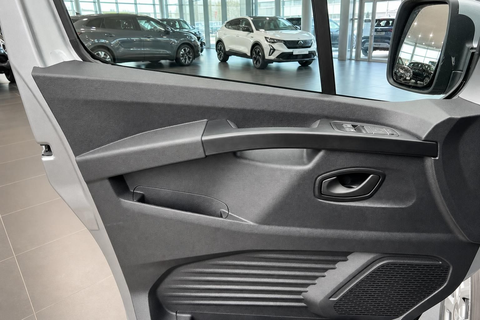 Fahrzeuginnenraum mit grauer Türverkleidung und Sicht auf Autohaus-Ausstellungsraum
