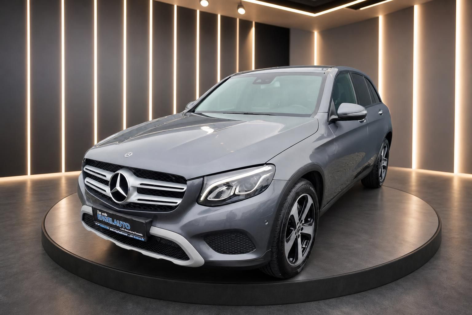 Mercedes GLC SUV grau metallic - Frontansicht schräg mit Händlerschild im Showroom