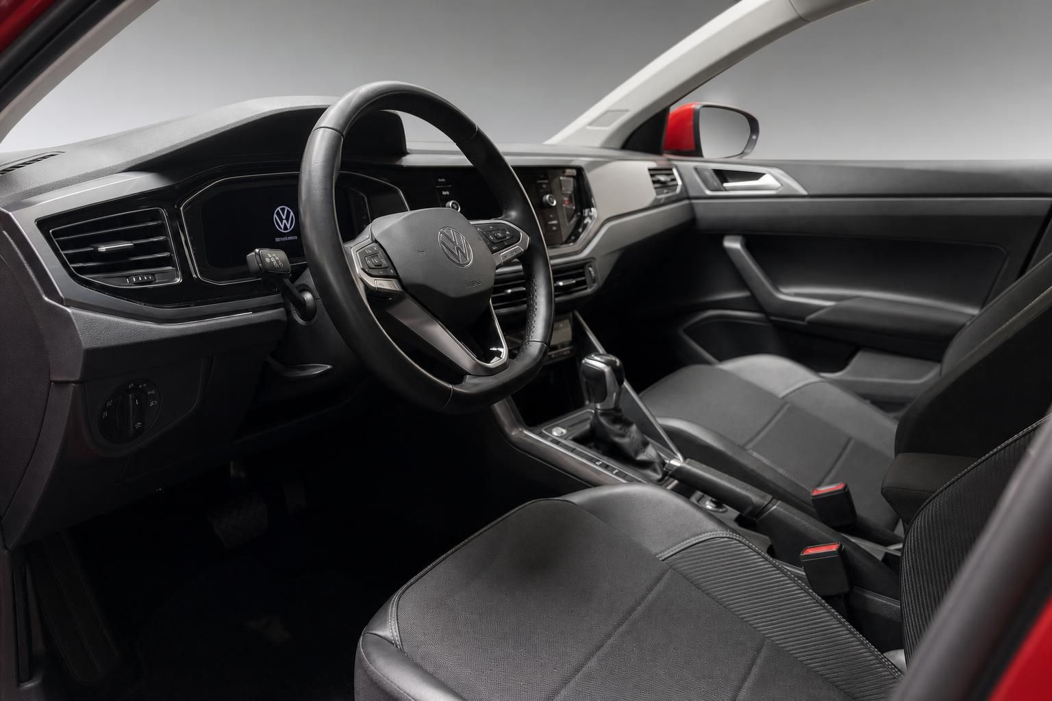 Innenraum eines roten VW mit schwarzem Lederlenkrad und Cockpit