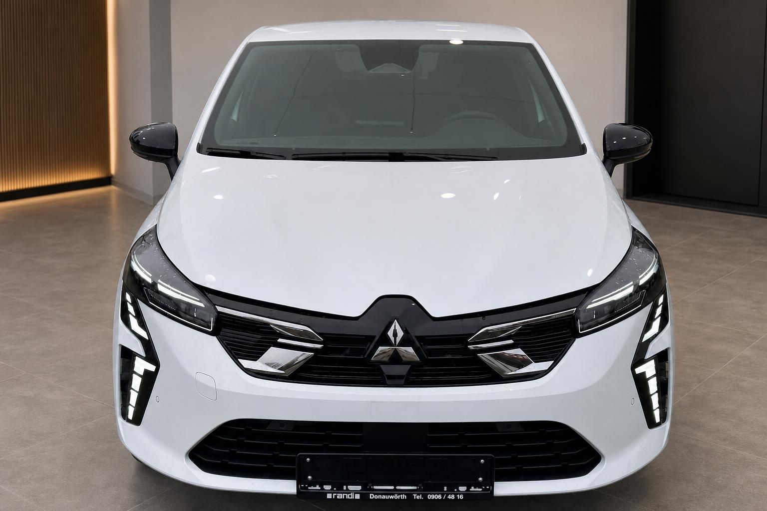 Renault Clio E-Tech weiss direkte Frontansicht mit LED-Scheinwerfern im Showroom