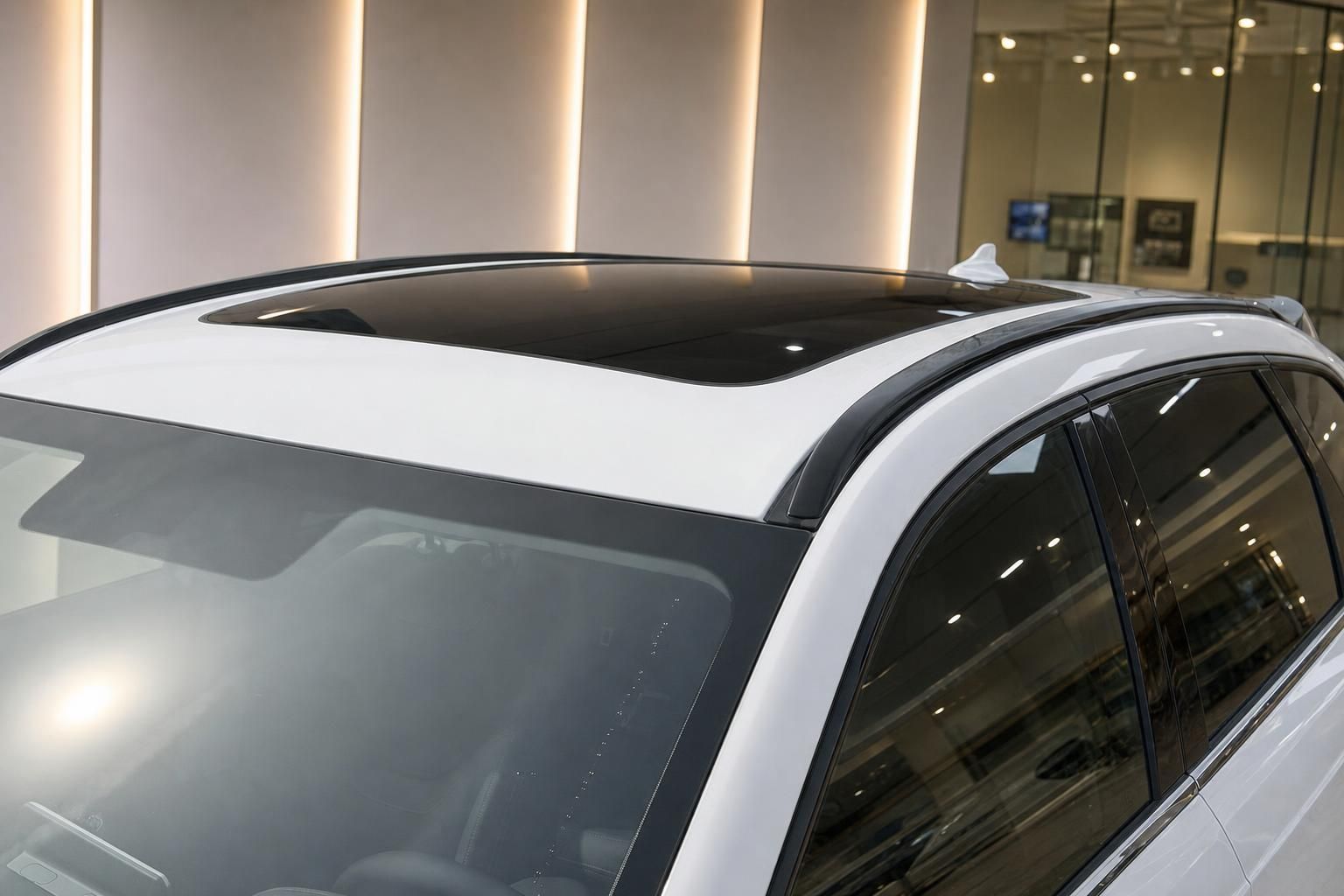 Weißes SUV mit Panorama-Glasdach und getönten Scheiben im Autohaus Seitenansicht