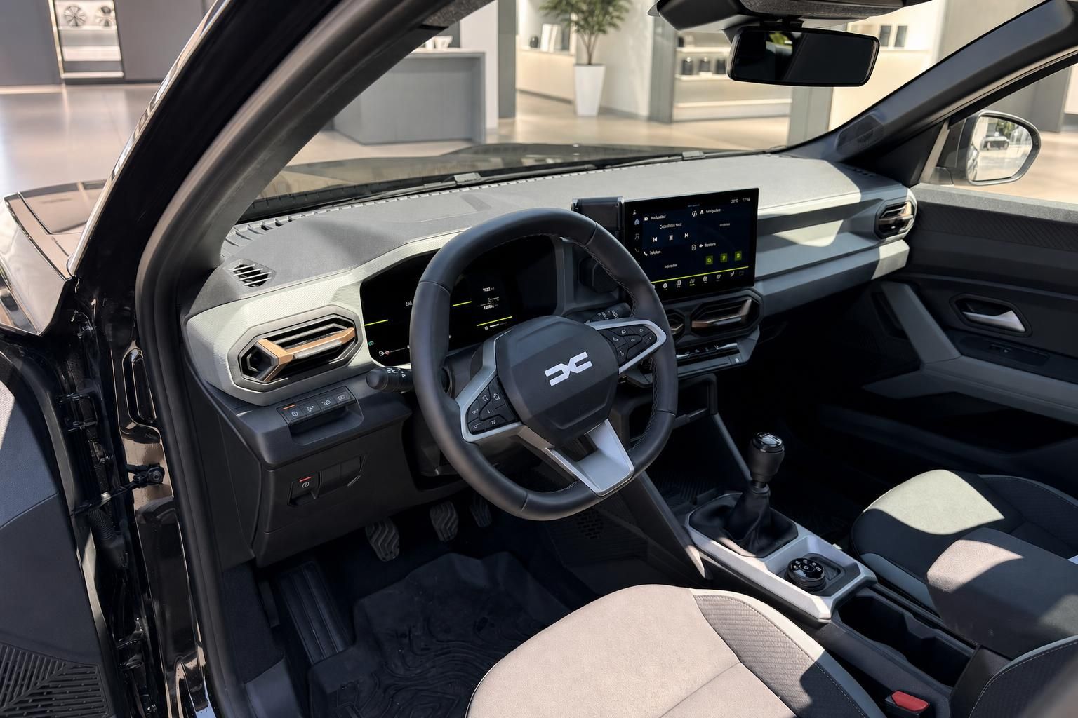 Dacia Fahrerraum mit offener Tür, Lenkrad und Cockpit im Autohaus