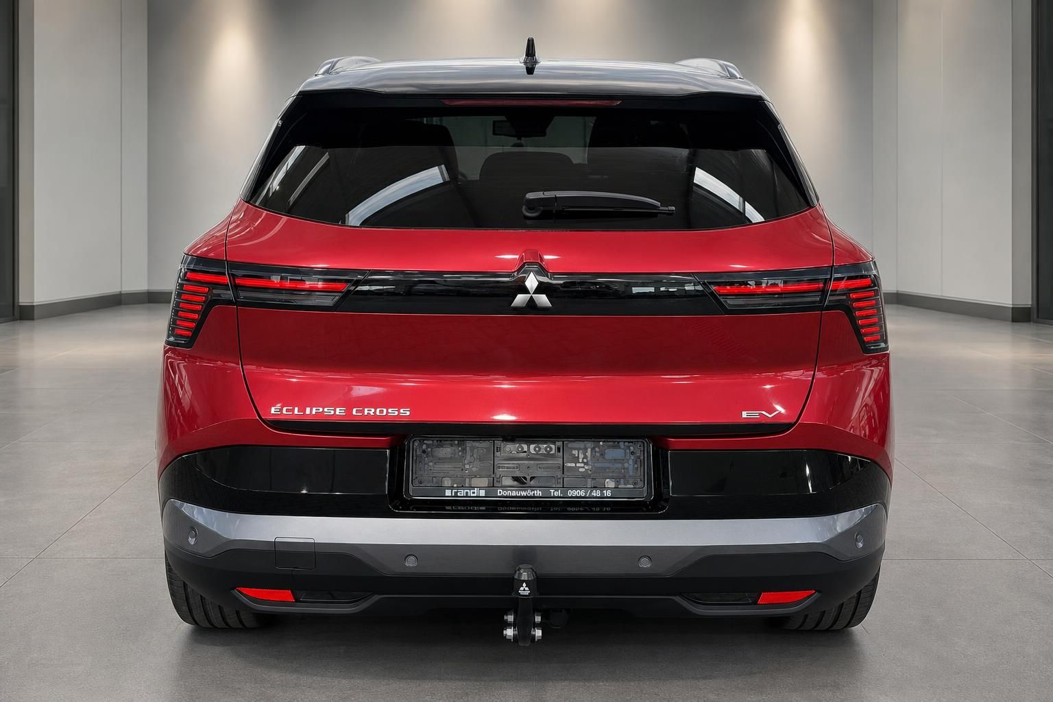 Mitsubishi Eclipse Cross EV rot – direkte Heckansicht mit Anhängerkupplung im Showroom