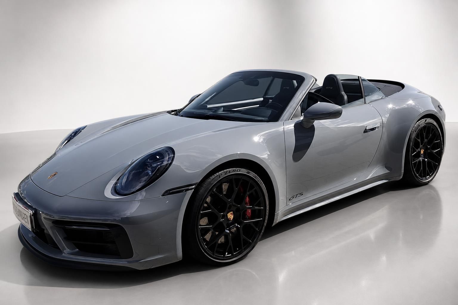 Porsche 911 GTS Cabrio in Grau mit schwarzen Sportfelgen, Frontansicht seitlich