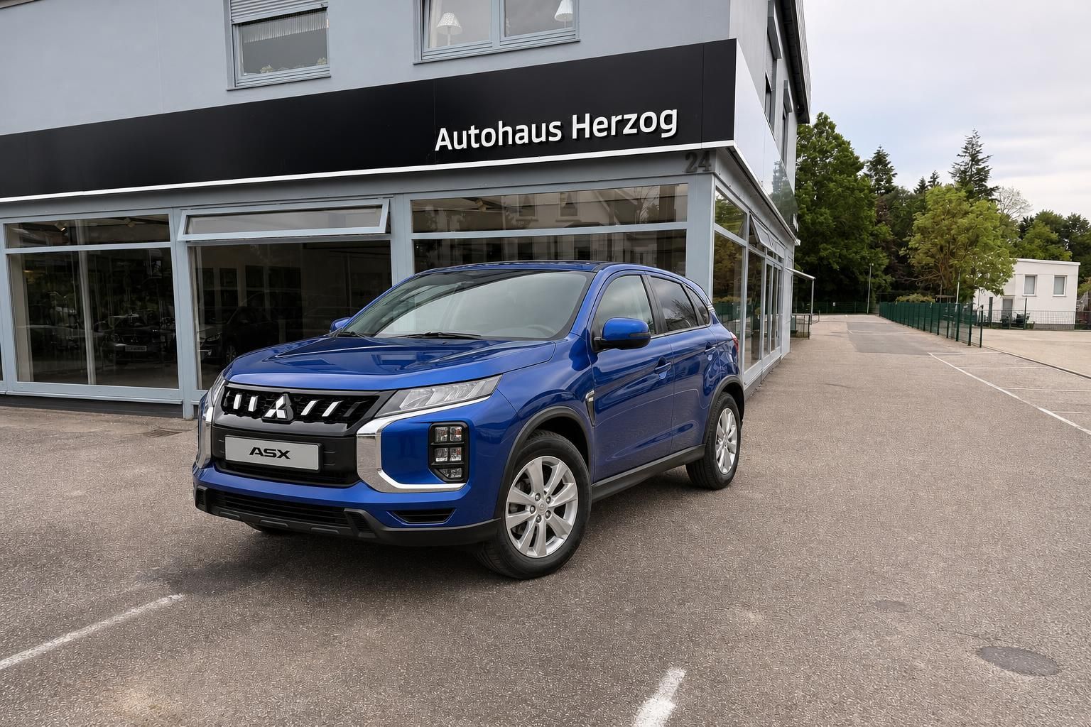 Blauer Mitsubishi ASX SUV vor Autohaus Herzog Showroom - Seitenansicht