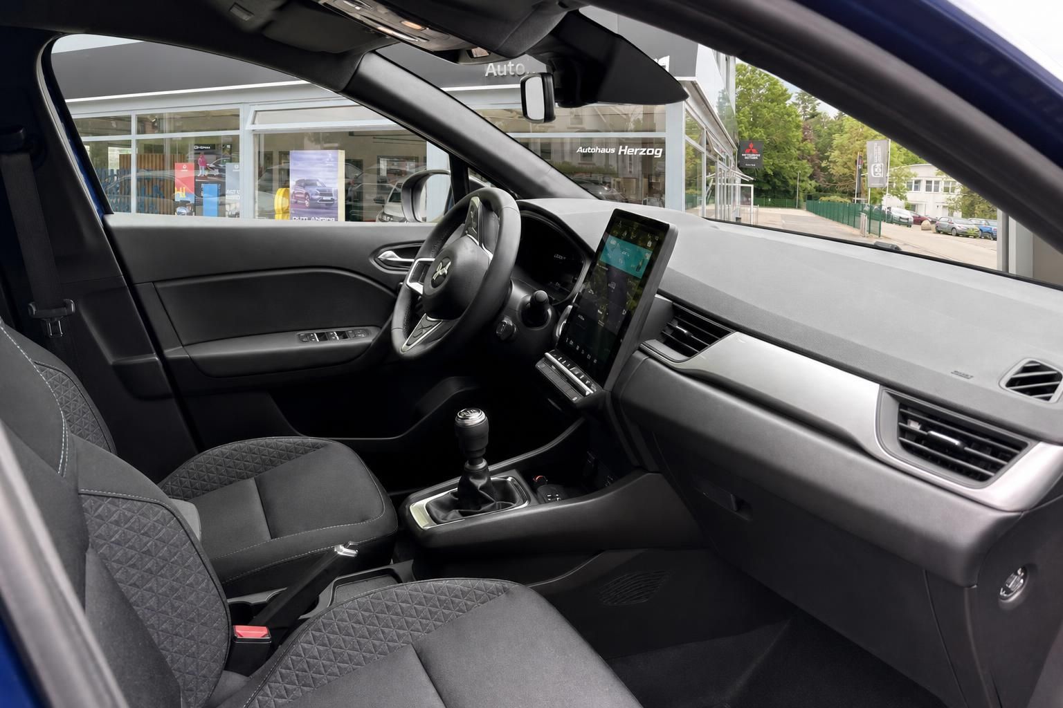 Innenraum eines Mitsubishi Fahrzeugs mit Schaltgetriebe und modernem Infotainmentsystem