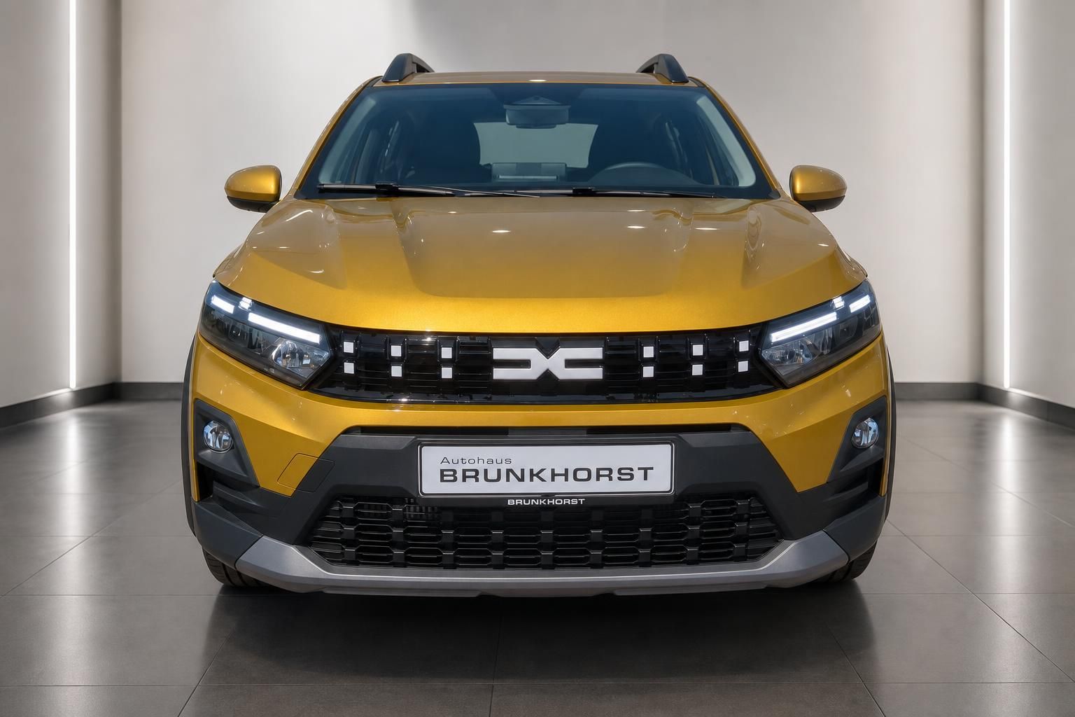 Dacia Sandero Stepway gelb, Frontansicht mit LED-Scheinwerfern im Showroom