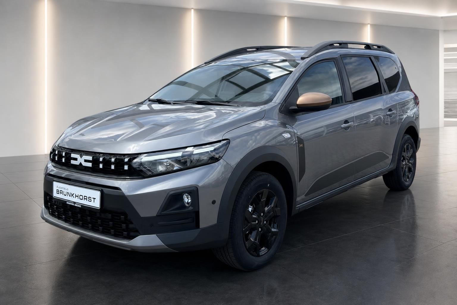 Grauer Dacia Jogger SUV in modernem Autohaus-Showroom - Frontansicht mit schwarzen Felgen
