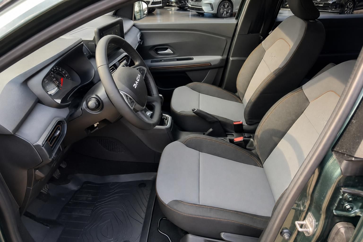 Dacia Fahrzeuginnenraum mit grauen Sitzen, Lenkrad und Cockpit-Ansicht von der Fahrerseite
