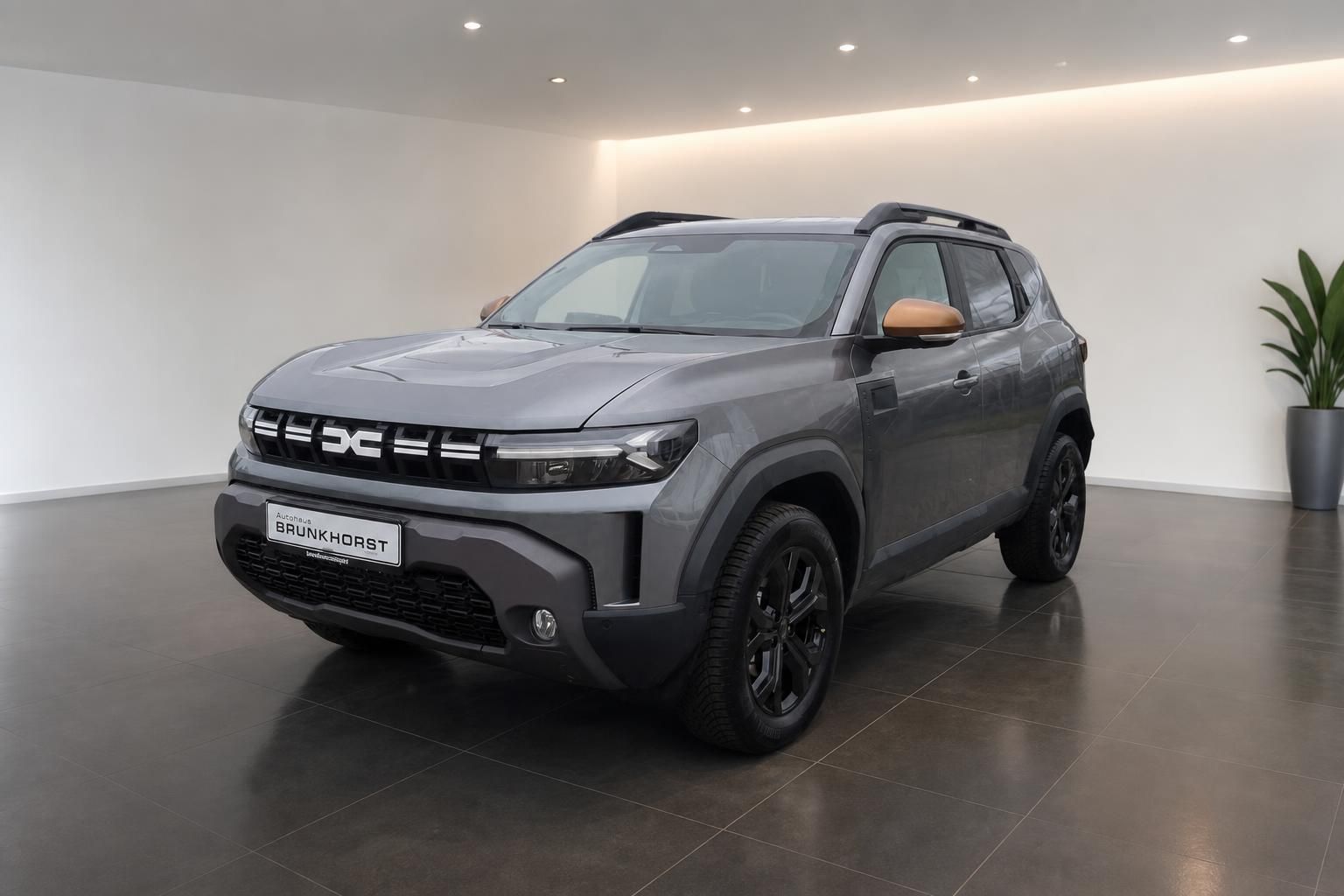Dacia Duster SUV Frontansicht grau metallic mit orange Akzenten im Autohaus Showroom
